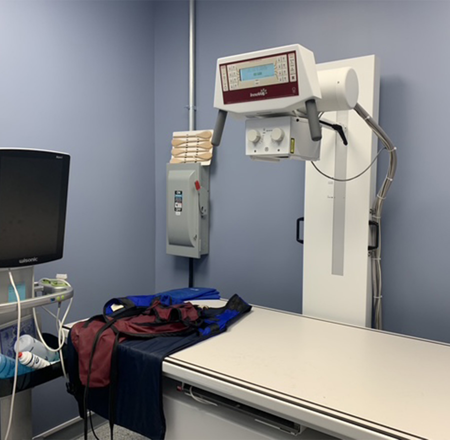 X-ray machine and exam table in a medical room.