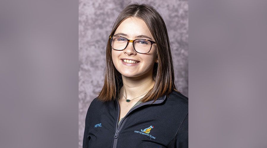 Young woman with glasses smiling in a branded jacket.