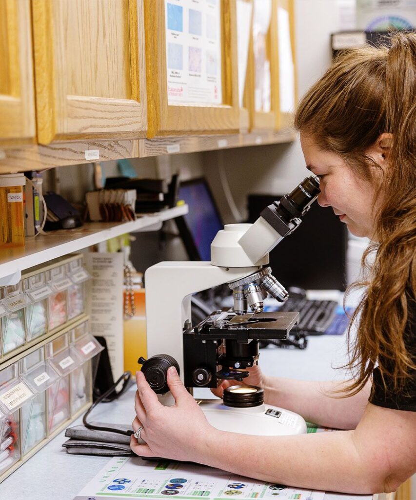 Woman using a microscope in a laboratory setting.
