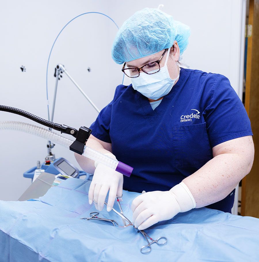 Veterinarian in scrubs performing surgery on an animal.